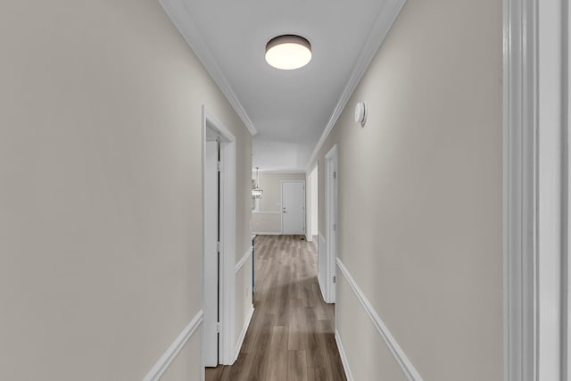 hallway featuring ornamental molding, baseboards, and wood finished floors