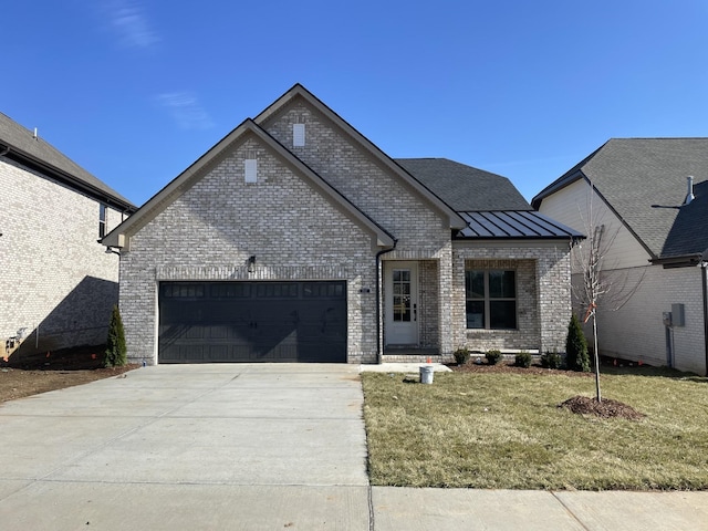 view of front of house featuring brick siding, a front yard, a garage, driveway, and a standing seam roof