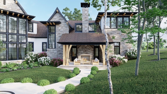 rear view of property featuring stone siding, a chimney, an outdoor stone fireplace, and a yard