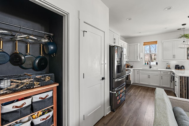 kitchen with dark wood-style floors, stainless steel appliances, decorative backsplash, a sink, and white cabinetry