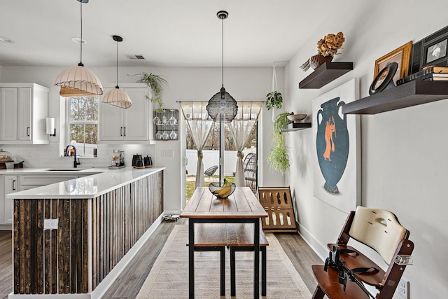 kitchen with visible vents, backsplash, white cabinetry, a peninsula, and light wood finished floors