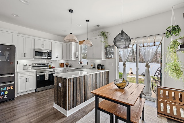 kitchen with dark wood-type flooring, white cabinetry, stainless steel appliances, a peninsula, and decorative backsplash