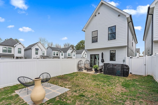 back of house featuring a lawn, a gate, a fenced backyard, a residential view, and a patio area