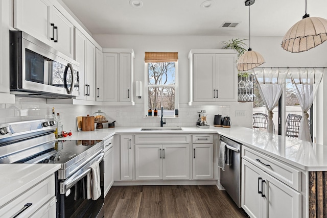 kitchen featuring tasteful backsplash, visible vents, appliances with stainless steel finishes, a peninsula, and a sink