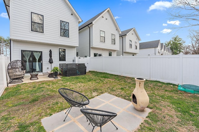 back of property with a patio area, a lawn, and a fenced backyard