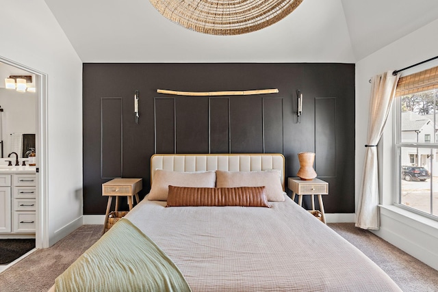 bedroom with baseboards, ensuite bath, lofted ceiling, a sink, and carpet flooring