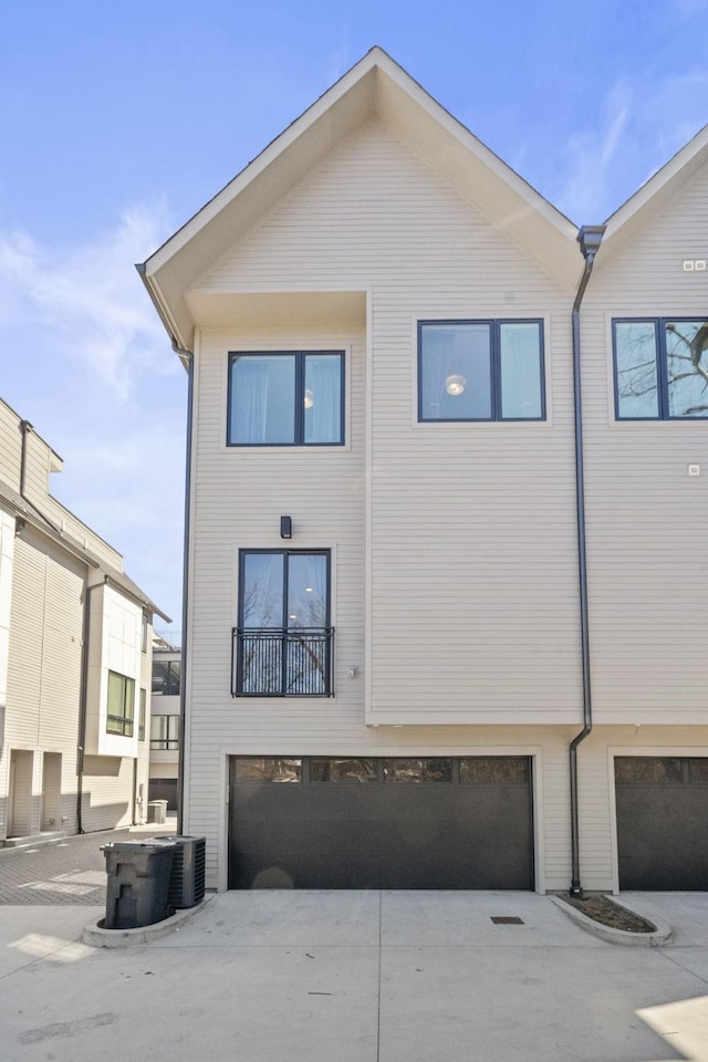 rear view of property featuring driveway and an attached garage