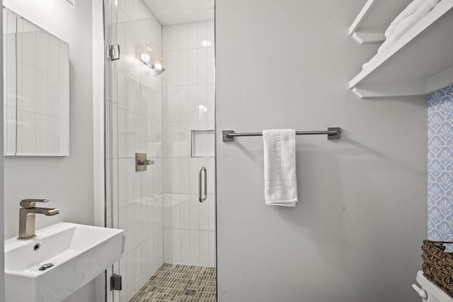 bathroom with a shower stall, toilet, and a sink