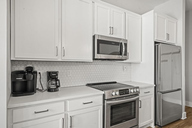 kitchen featuring tasteful backsplash, light countertops, wood finished floors, white cabinets, and stainless steel appliances