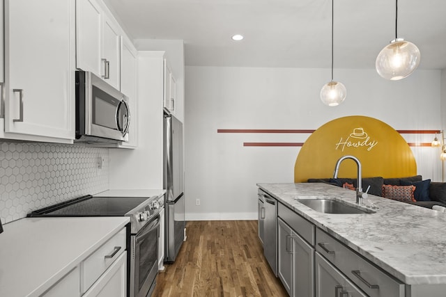 kitchen featuring tasteful backsplash, dark wood finished floors, stainless steel appliances, white cabinetry, and a sink