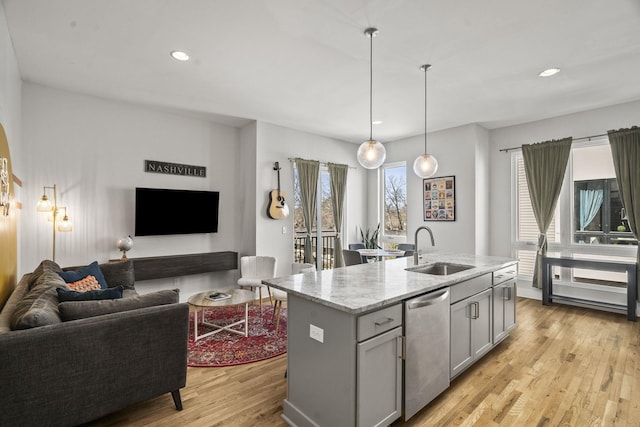 kitchen featuring light wood finished floors, open floor plan, dishwasher, and a sink