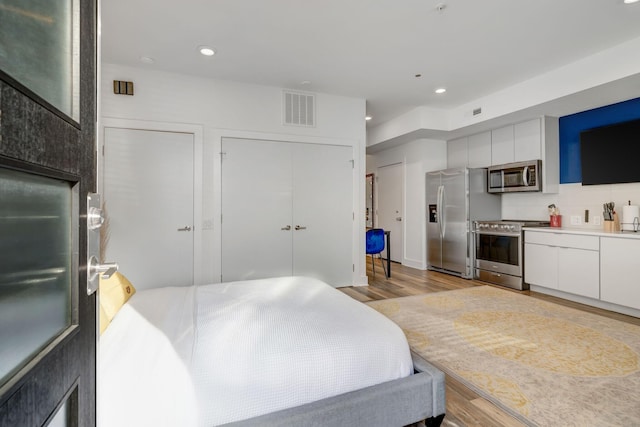 bedroom featuring visible vents, recessed lighting, light wood-style floors, and stainless steel fridge with ice dispenser