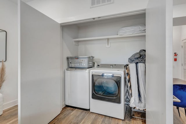 washroom with visible vents, separate washer and dryer, wood finished floors, and laundry area