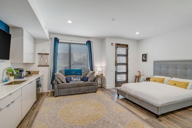 bedroom with baseboards, recessed lighting, light wood-type flooring, and a sink