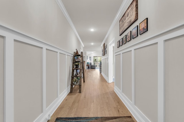 corridor featuring a decorative wall, recessed lighting, light wood-type flooring, and crown molding