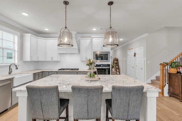 kitchen featuring light stone countertops, a sink, ornamental molding, stainless steel appliances, and a center island