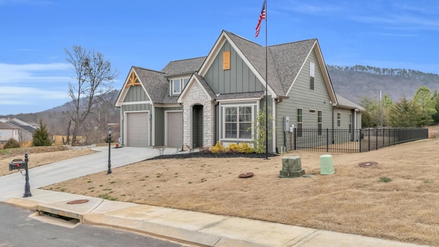 view of front of house featuring fence, concrete driveway, a garage, board and batten siding, and a mountain view