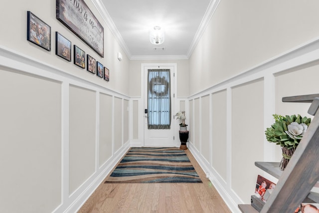 doorway to outside with a decorative wall, wood finished floors, visible vents, and ornamental molding