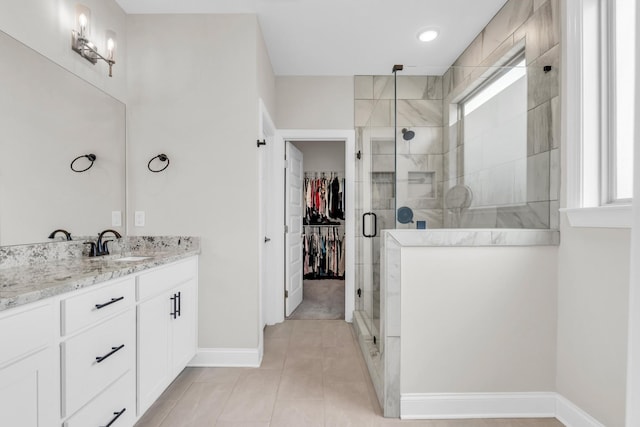 full bath with tile patterned floors, a shower stall, baseboards, a spacious closet, and vanity