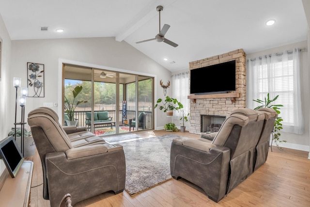 living area with visible vents, vaulted ceiling with beams, ceiling fan, light wood-type flooring, and a fireplace