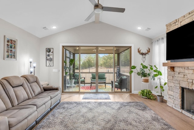 living area with a stone fireplace, plenty of natural light, a ceiling fan, and vaulted ceiling with beams