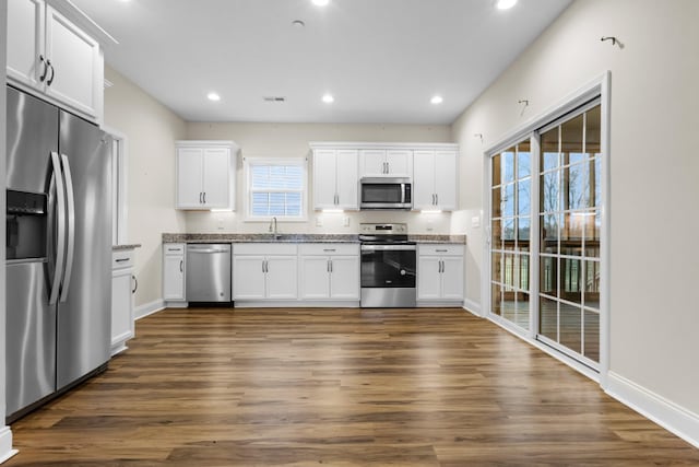 kitchen with a sink, stainless steel appliances, white cabinets, and recessed lighting