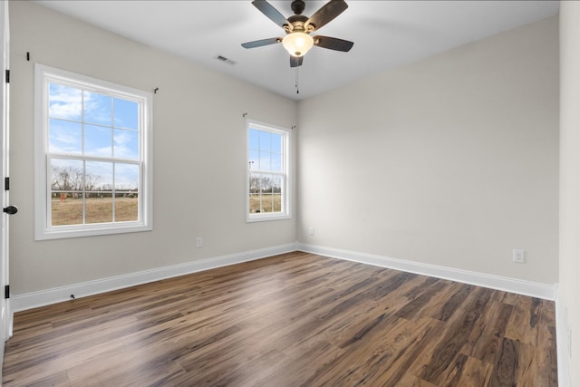 unfurnished room with visible vents, a ceiling fan, dark wood-type flooring, and baseboards