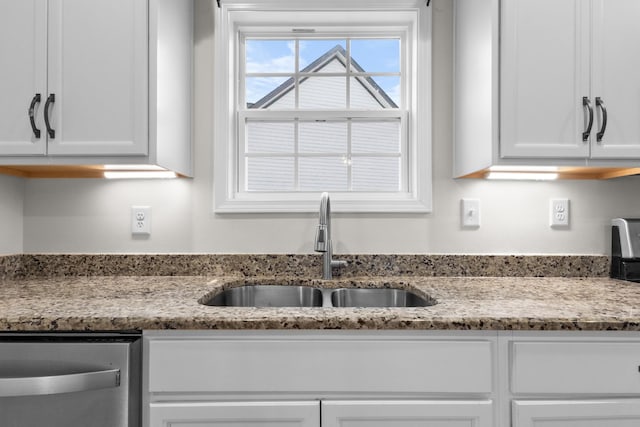 kitchen featuring a sink, light stone counters, stainless steel dishwasher, and white cabinets