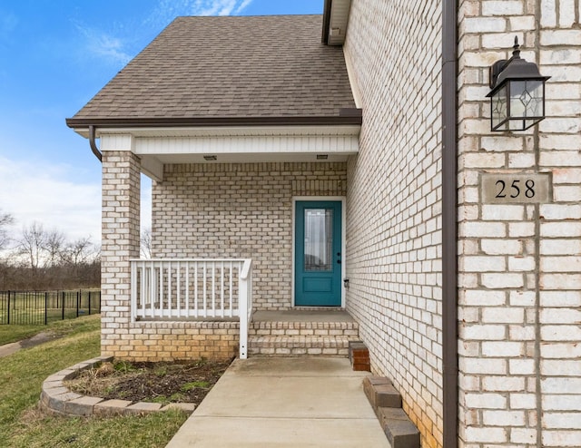 entrance to property featuring a porch and roof with shingles