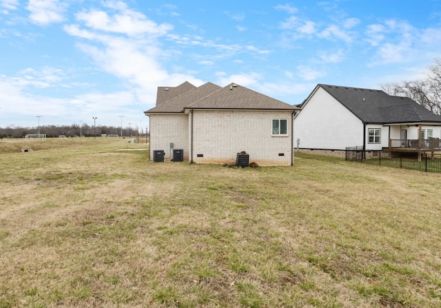 exterior space featuring fence, a yard, roof with shingles, crawl space, and brick siding