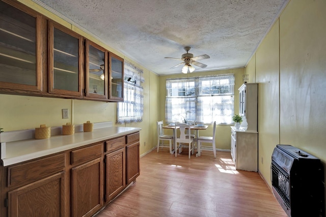 kitchen with glass insert cabinets, ceiling fan, light wood-type flooring, light countertops, and heating unit