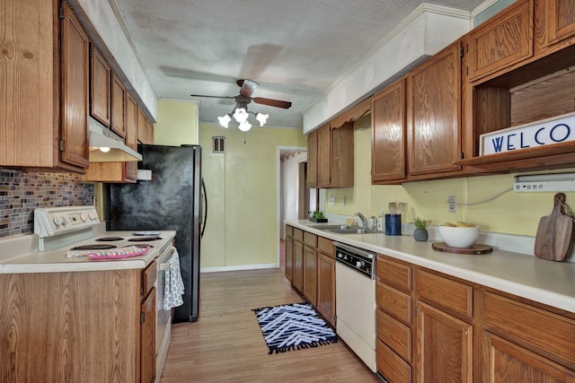 kitchen with under cabinet range hood, light countertops, brown cabinetry, white appliances, and a ceiling fan