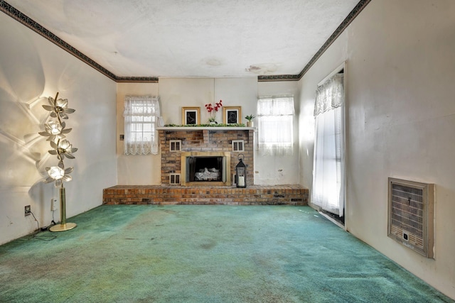 unfurnished living room with heating unit, carpet flooring, a fireplace, and crown molding