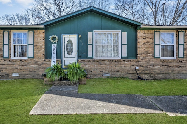 view of front facade featuring crawl space, brick siding, and a front yard