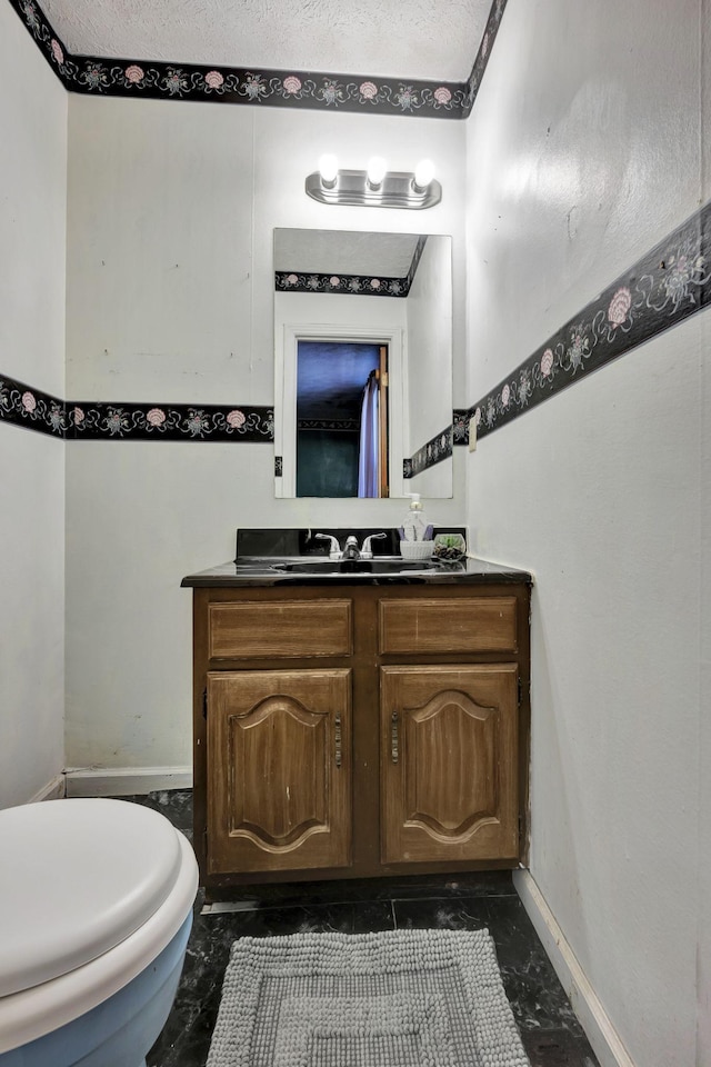 half bathroom with vanity, baseboards, a textured ceiling, toilet, and marble finish floor