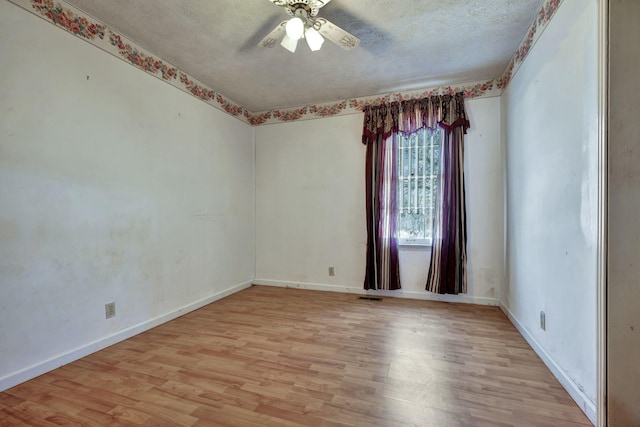 unfurnished room featuring a textured ceiling, light wood-style flooring, baseboards, and ceiling fan