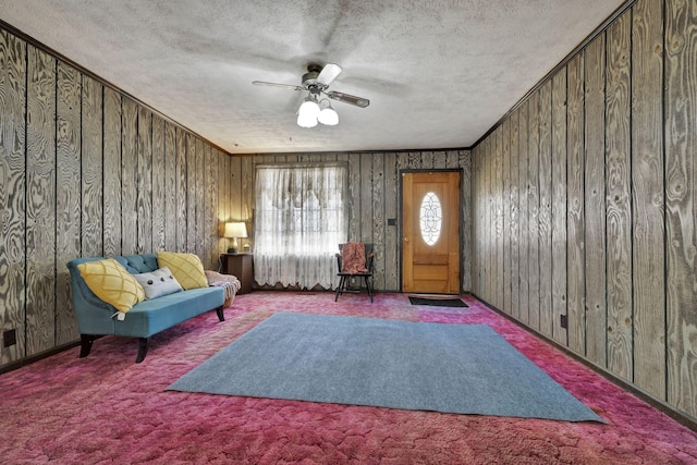 living area with ornamental molding, a ceiling fan, carpet floors, and a textured ceiling