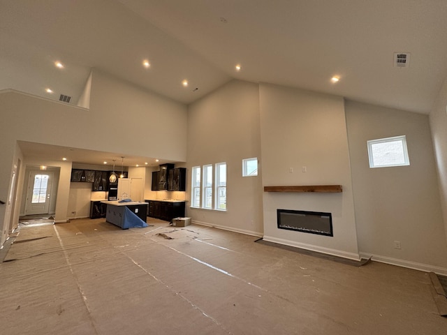 living room with a healthy amount of sunlight, high vaulted ceiling, and baseboards