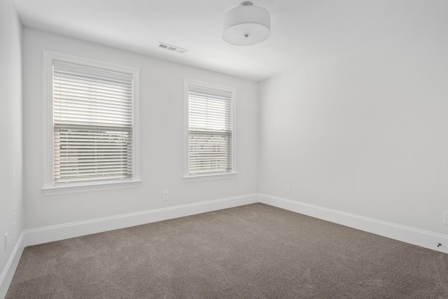 carpeted spare room featuring visible vents and baseboards