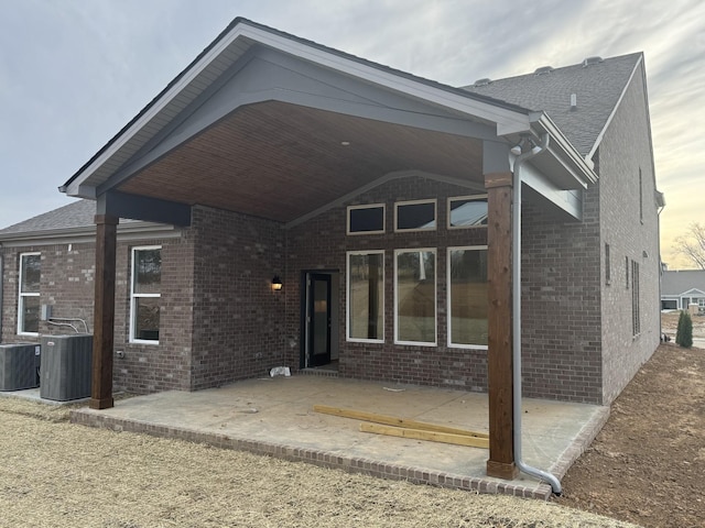 back of property with a patio, cooling unit, and brick siding