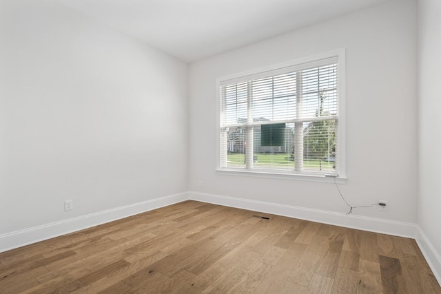 empty room featuring visible vents, baseboards, and light wood finished floors