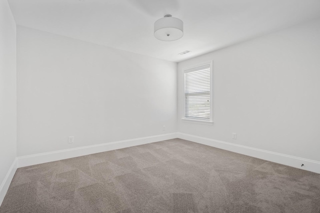 carpeted spare room with visible vents and baseboards