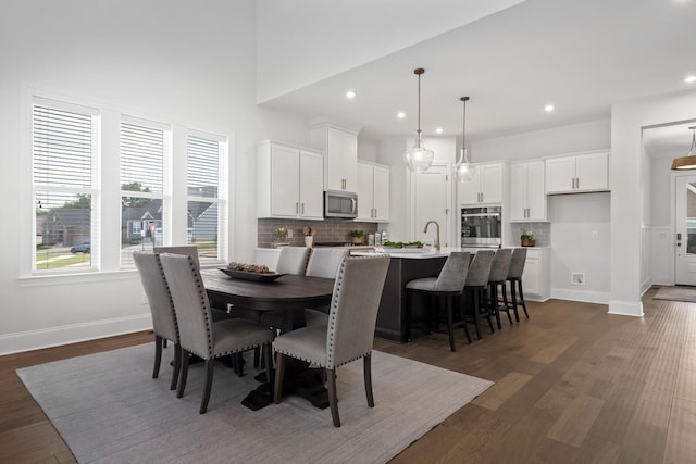 dining room featuring dark wood finished floors, recessed lighting, baseboards, and a towering ceiling