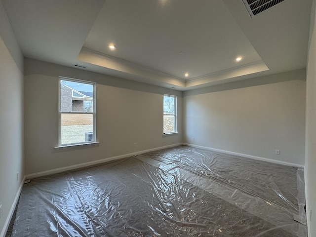 spare room featuring a raised ceiling, baseboards, and visible vents