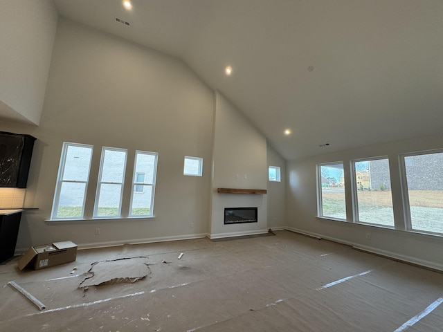 unfurnished living room with baseboards, visible vents, high vaulted ceiling, recessed lighting, and a glass covered fireplace