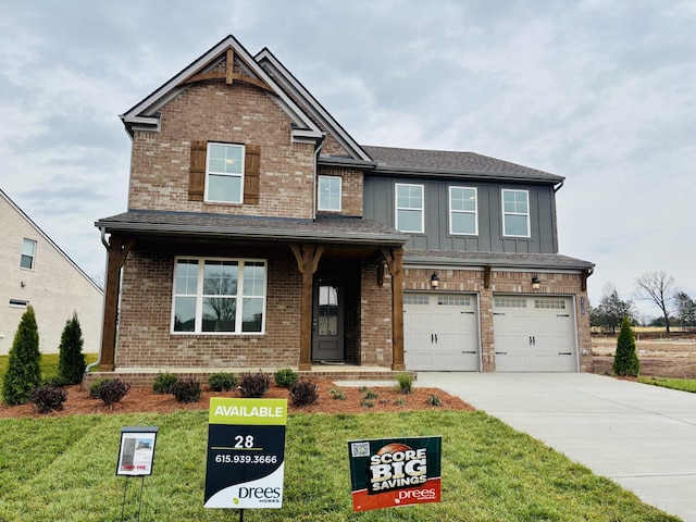 craftsman-style house with brick siding, board and batten siding, a front lawn, concrete driveway, and an attached garage