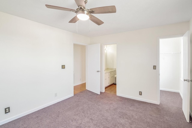 unfurnished bedroom with a walk in closet, baseboards, light colored carpet, and a closet