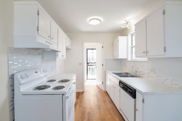 kitchen with a sink, under cabinet range hood, white appliances, light wood finished floors, and light countertops