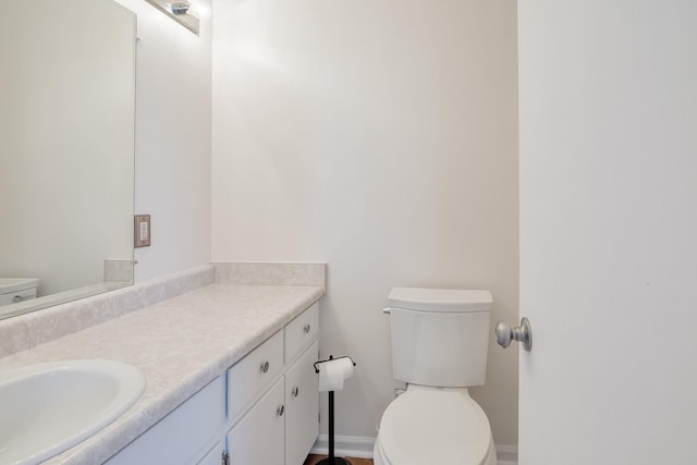 half bath featuring toilet, vanity, and baseboards