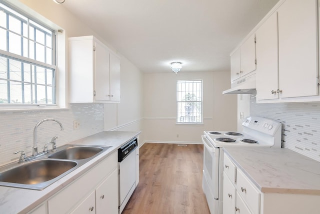 kitchen with white appliances, a sink, white cabinets, under cabinet range hood, and light wood-type flooring